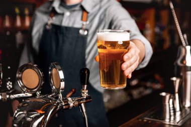 Barmen, barın iç tarafındaki müşteriye light bira servisi yapıyor.