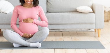 Siyah kadın evde egzersiz yaparken koca göbeğine dokunuyor.