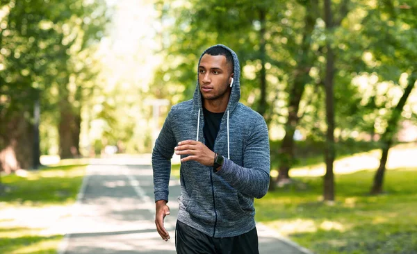 Millennial běžec se sluchátky těší jeho ranní běh v letním parku, prázdné místo — Stock fotografie