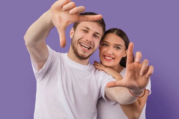 Beautiful young couple is making frame, looking at camera — Stock Photo, Image