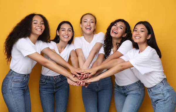 Cinco United Diverse Girls segurando as mãos posando no fundo amarelo — Fotografia de Stock