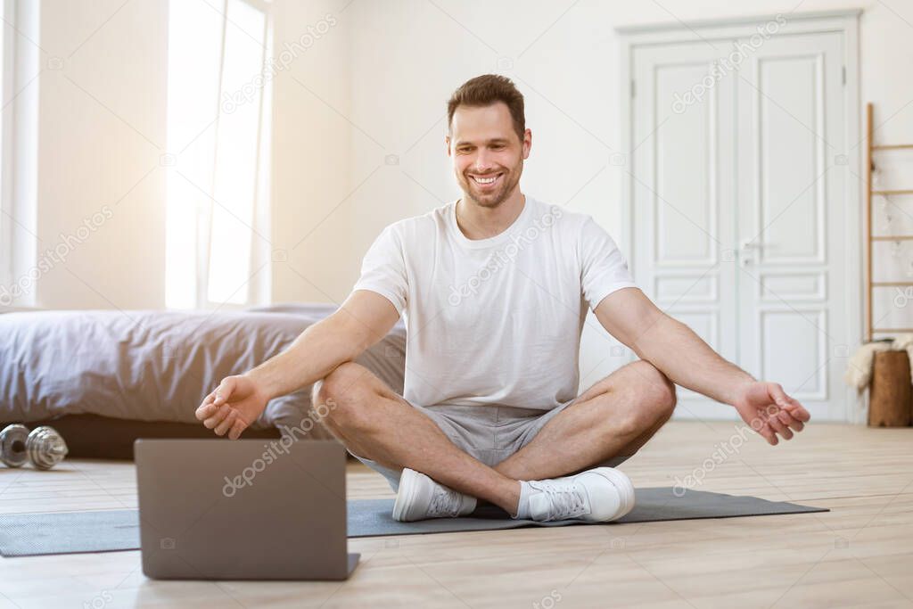 Man Doing Yoga At Home Sitting In Lotus Position Indoors