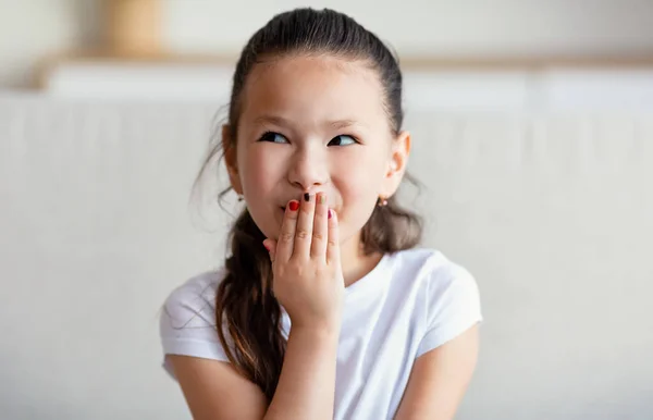 Chinese Girl Chuckling Covering Mouth Sitting On Sofa At Home — Stock Photo, Image