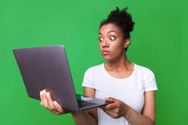 Excited black girl feeling surprised holding laptop