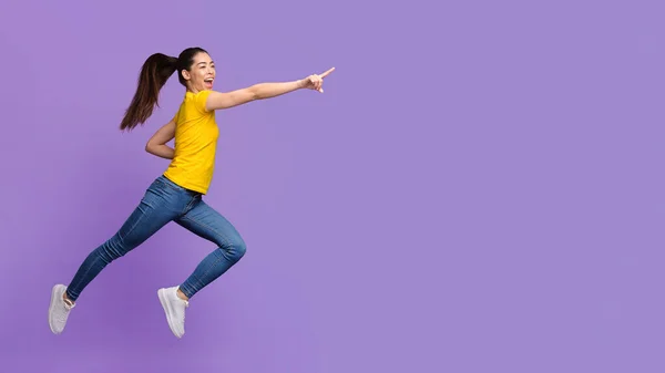 Titta där. Spännande asiatiska flicka hoppa och peka bort på kopiera utrymme — Stockfoto