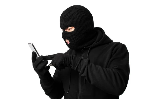 Maskeli kötü adam akıllı bir telefon ekranına dokunuyor — Stok fotoğraf