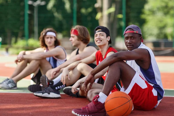 Equipo multirracial de jugadores de baloncesto descansando un poco después de su juego en la cancha al aire libre, espacio de copia — Foto de Stock