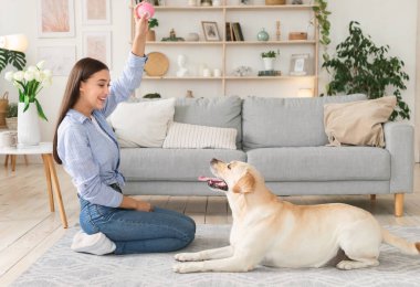 Oturma odasında köpekle oynayan güzel bir kadın.
