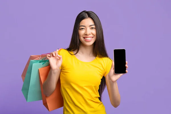ショッピングアプリ。アジアの女の子保持スマートフォン付きブラックスクリーンとショッパーバッグ — ストック写真