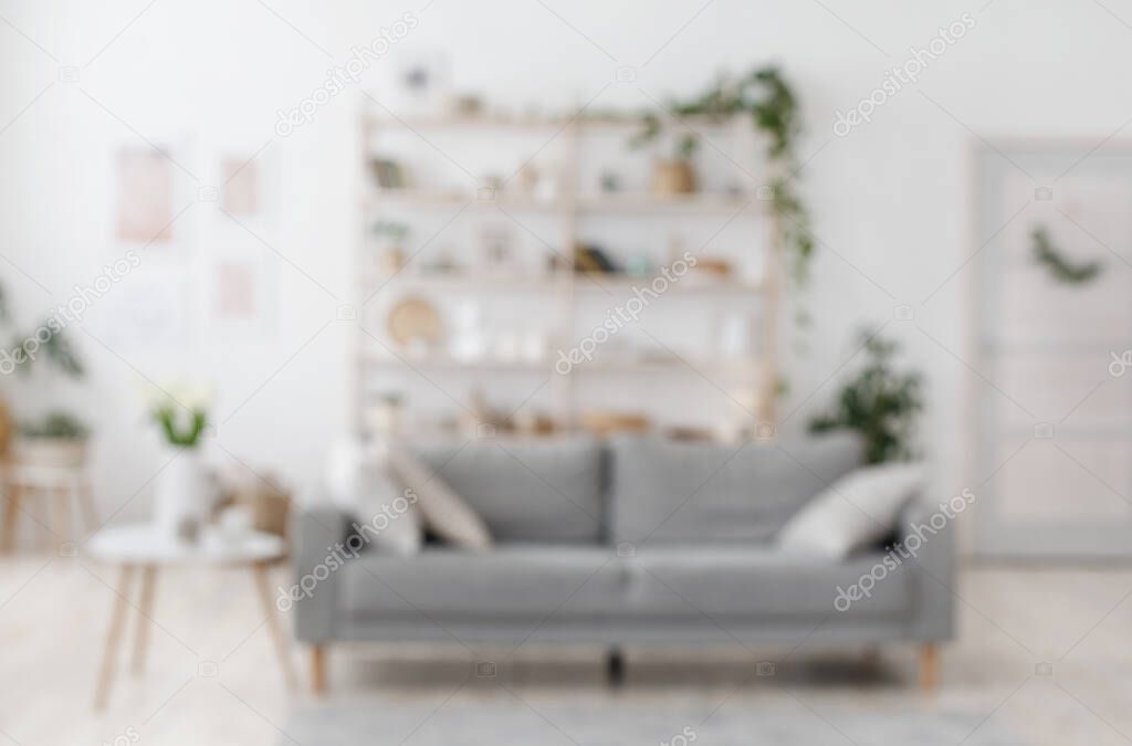 Blurred image of modern living room interior with grey sofa