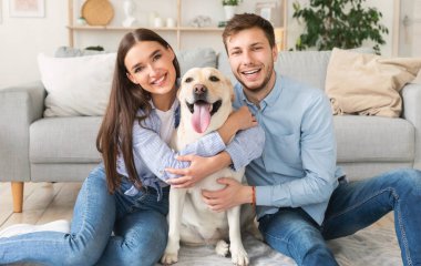 Genç, mutlu eşler ve köpekleri oturma odasında oturuyor.