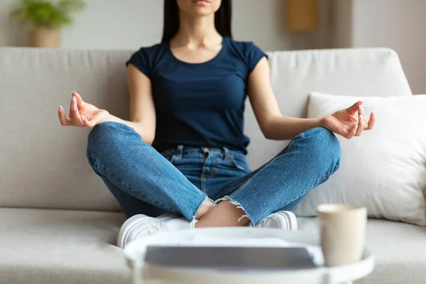 Vrouw die mediteert zittend in lotuspositie op de bank binnen, gegrepen — Stockfoto