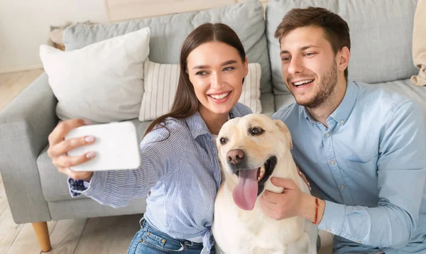 Jeune couple prenant autoportrait avec chien à la maison — Photo