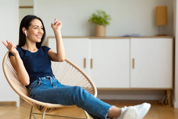 Donna con auricolari godendo di musica seduta in sedia a casa — Foto Stock
