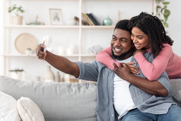 ロマンティック・セルフィー。自宅でスマートフォンで写真を撮る幸せな愛する黒人カップル — ストック写真