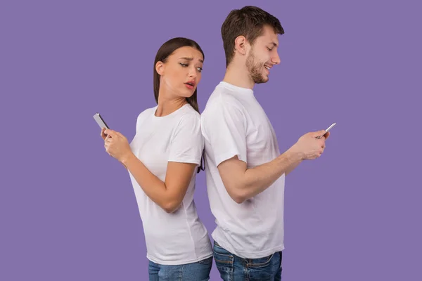 Retrato de pareja joven de pie espalda con espalda usando teléfonos — Foto de Stock