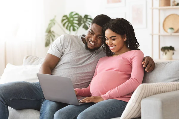 Casal grávida se divertindo em casa, usando laptop juntos — Fotografia de Stock