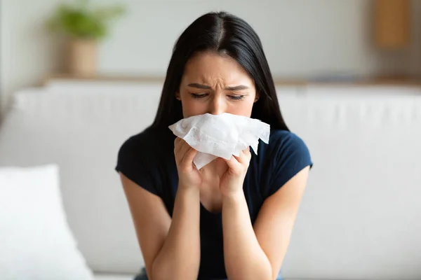 Krankes Mädchen niest Nase pustet in Papiergewebe, das drinnen sitzt — Stockfoto