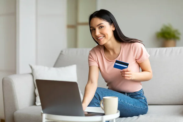 Mujer en el ordenador portátil celebración de compras con tarjeta de crédito en línea en casa —  Fotos de Stock