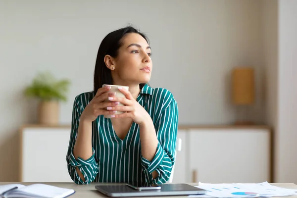 Menina tomando café sentado no escritório, desfrutando de pausa no local de trabalho — Fotografia de Stock