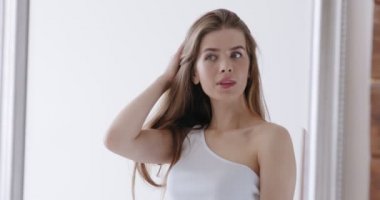 Genç kadın aynaya bakıyor, kendini güzelleştiriyor.