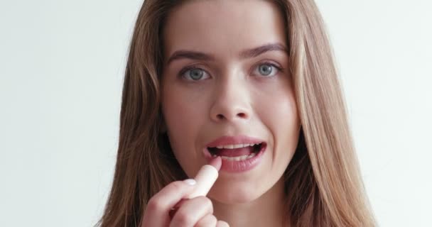 Mujer joven que aplica lápiz labial rosa, cuidando sus labios — Vídeo de stock