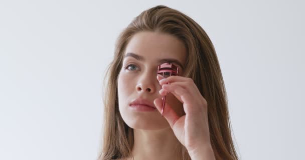 Young girl curling her eyelashes, using special curler — Stock Video