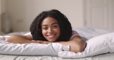 Yatakta yatan mutlu Afro-Amerikan kız portresi.