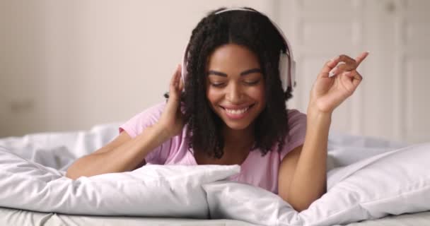 Aktivní tisíciletá africká americká dívka těší hudbu v posteli — Stock video