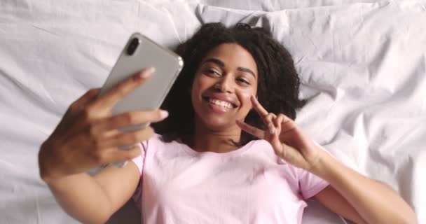 Hübsches afrikanisches amerikanisches Mädchen macht Selfie auf Handy im Bett — Stockvideo