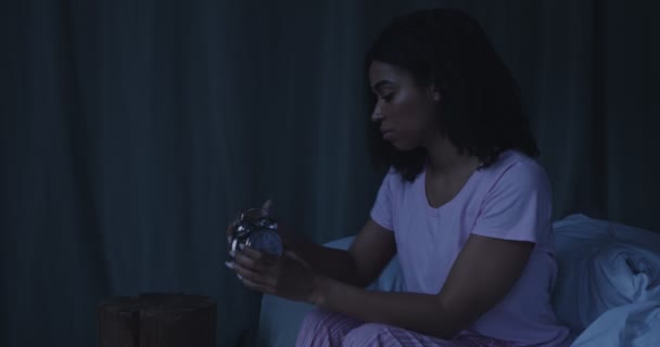 Joven mujer afroamericana poniendo despertador antes de dormir — Vídeo de stock