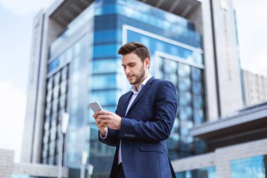 Şehir merkezinde akıllı telefondan internette gezinen genç girişimci
