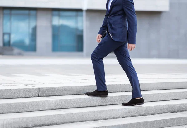 Corporate employee going up stairs on way to his work near office building, empty space