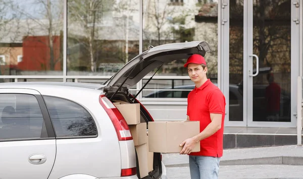 Consegna in auto a domicilio. Corriere prende grande scatola dal tronco — Foto Stock