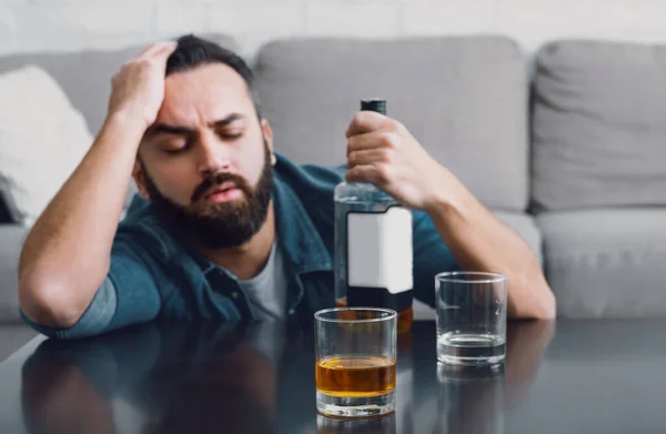 Depressionen und Alkoholismus zu Hause. Mann schläft ein und hält Flasche — Stockfoto