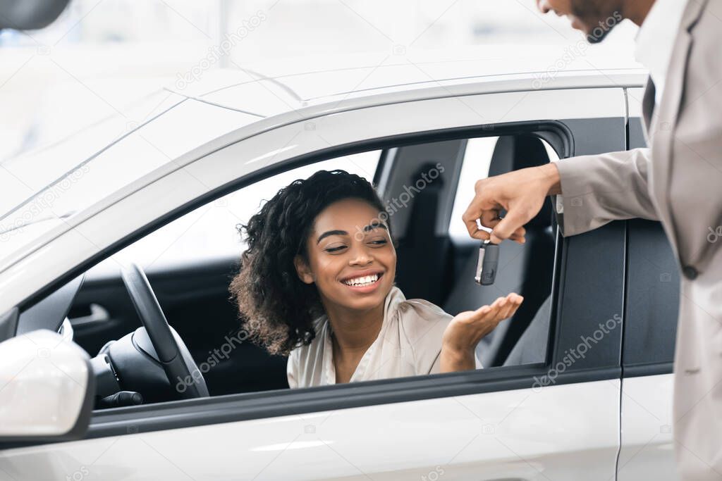Seller Giving Lady Key For Test Drive In Dealership Showroom