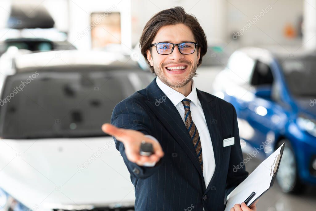 Seller Showing Key Standing In Automobile Rental Office