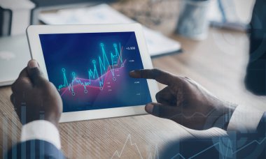 Tablet bilgisayarla çalışan Afrikalı Amerikalı girişimci, ofiste artan finansal grafikler, kolaj