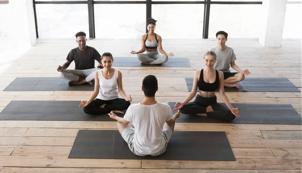 Grupo de jóvenes que tienen clase de yoga con coach en estudio — Foto de Stock