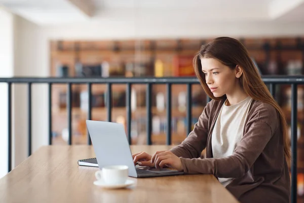 Studentessa sorridente con caffè e laptop che lavora nel caffè — Foto Stock