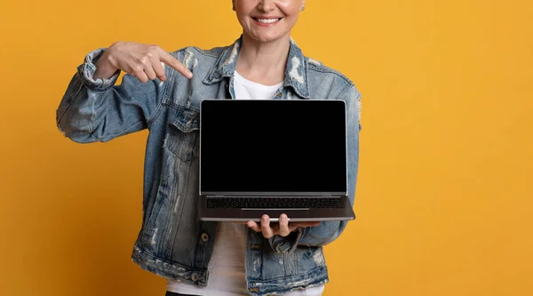 Neue Webseite. Unerkennbare Dame mittleren Alters zeigt mit leerem schwarzen Bildschirm auf Laptop — Stockfoto