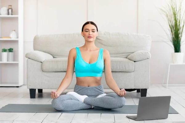 Мирна жінка медитує під час онлайн йоги вдома — стокове фото