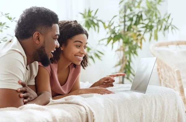 Sidovy av glada afrikanska par som använder laptop i sängen — Stockfoto