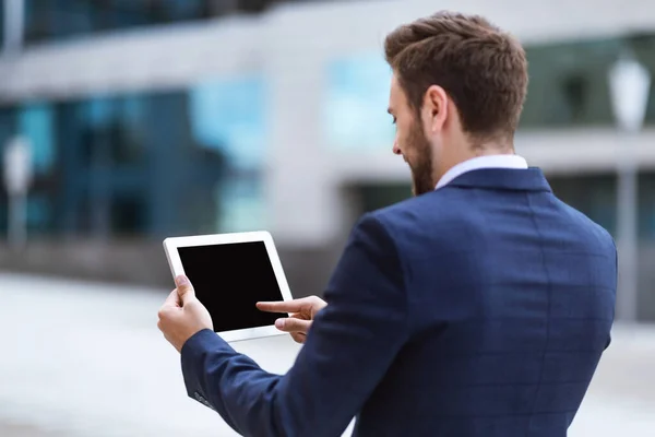 Business executivo segurando tablet computador com tela em branco perto de prédio de escritórios, mockup para design — Fotografia de Stock