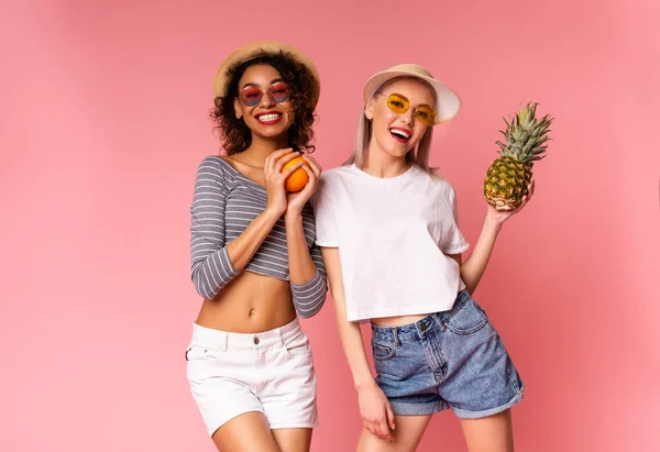 Duas garotas Funky em roupas de verão elegantes posando com frutas exóticas frescas — Fotografia de Stock