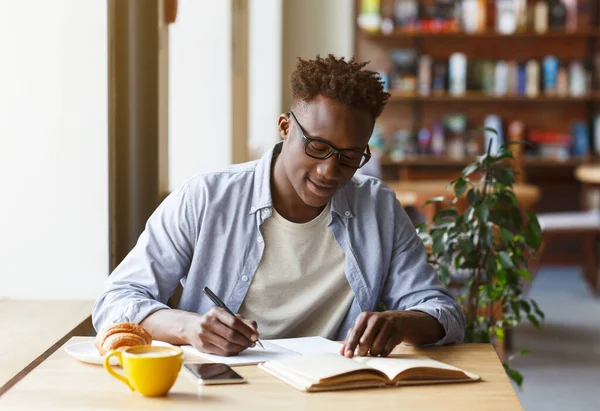 Молодий афроамериканець вчиться у сучасній кафе. — стокове фото