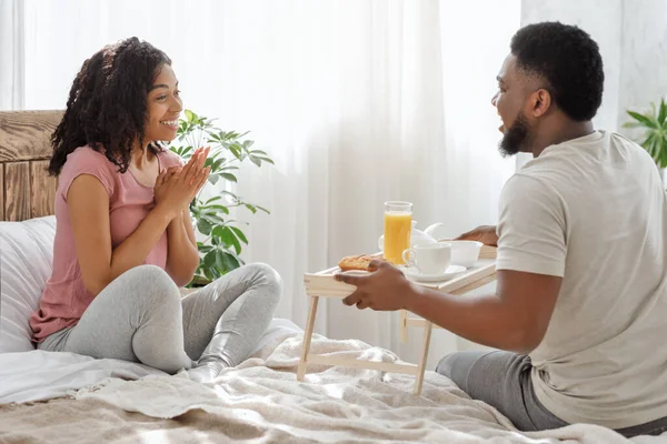 Happy african woman surprised with breakfast in bed