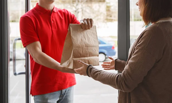 Eve kuryeyle teslimat var. Teslimatçı kız müşteriye kağıt paket veriyor. — Stok fotoğraf