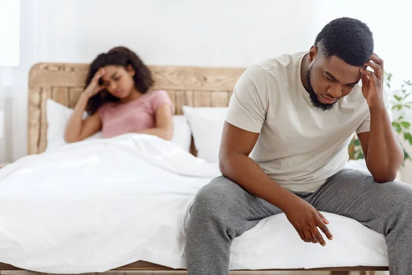 Triste hombre y mujer después de pelearse sentados en la cama —  Fotos de Stock