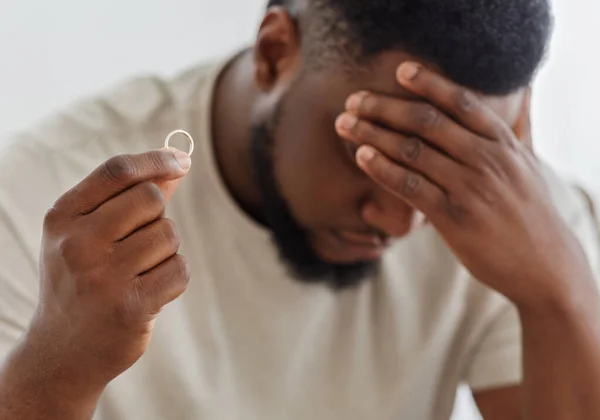 Desperate black guy holding marriage ring, thinking about divorce — Stock Photo, Image